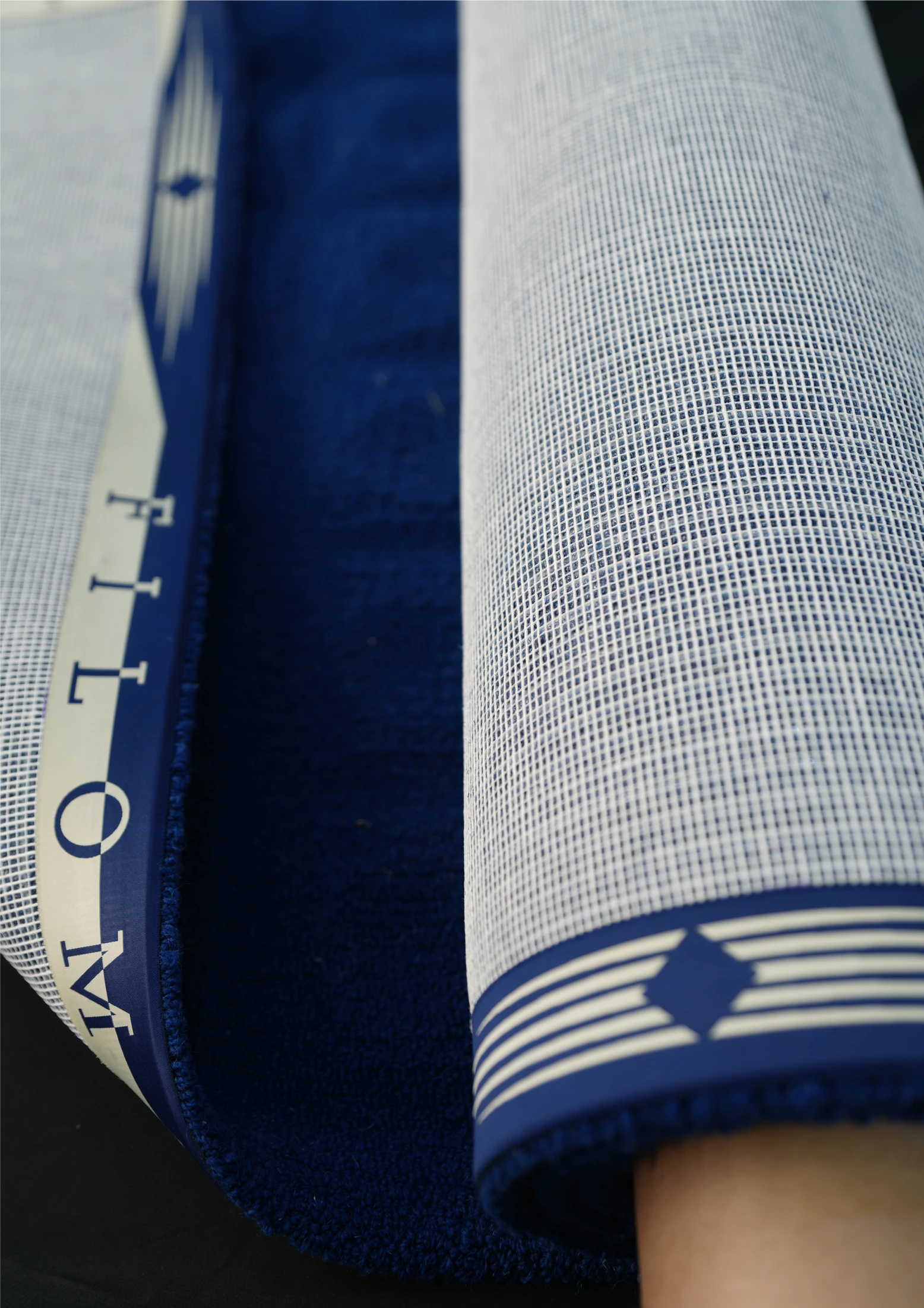 Reverso de una alfombra azul enrollada con cinta perimetral Filomaestro.